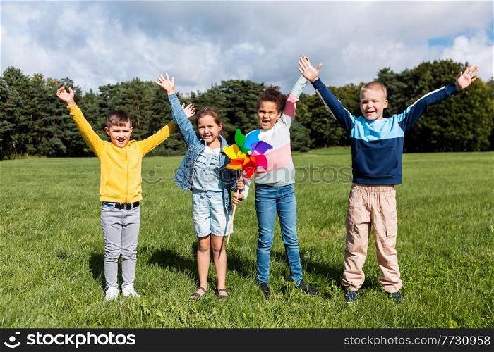 childhood, leisure and people concept - group of happy kids with pinwheel having fun at park. happy kids with pinwheel having fun at park