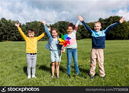 childhood, leisure and people concept - group of happy kids with pinwheel having fun at park. happy kids with pinwheel having fun at park