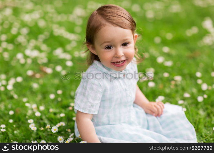 childhood, leisure and people concept - happy baby girl on green summer field. happy baby girl on green summer field