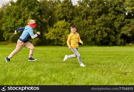 childhood, leisure and people concept - happy boys playing seek and hide game at park. happy boys playing seek and hide game at park