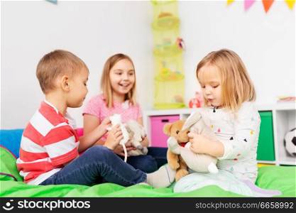 childhood, leisure and people concept - happy children playing with soft toys at home. happy children playing with soft toys at home