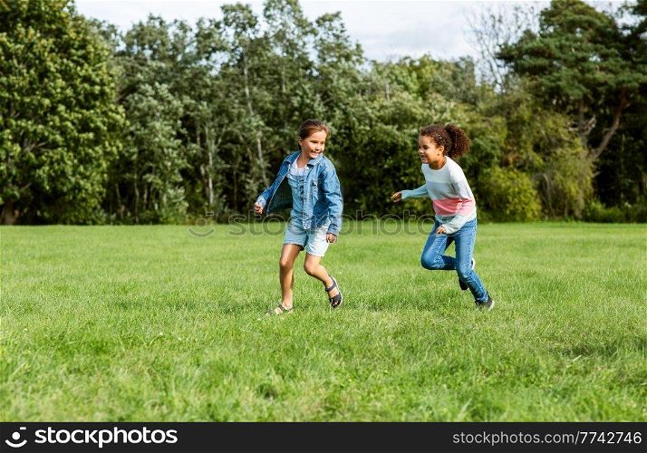 childhood, leisure and people concept - happy girls playing tag game and running at park. happy girls playing and running at park