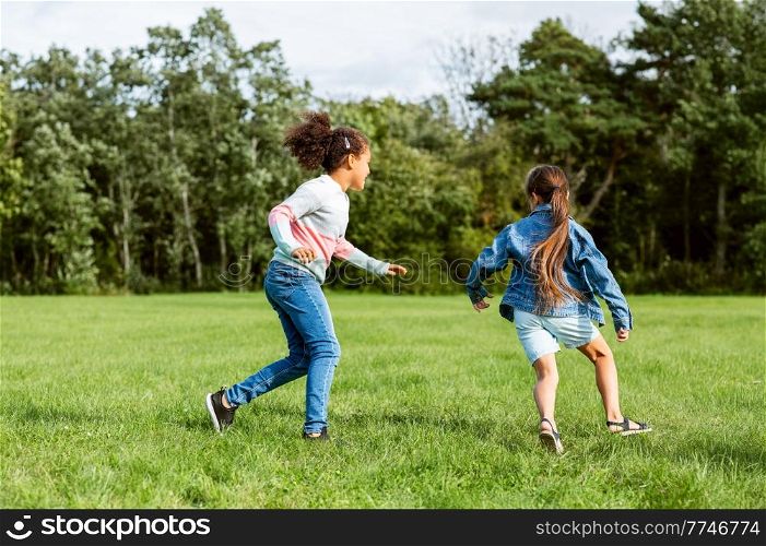 childhood, leisure and people concept - happy girls playing tag game and running at park. happy girls playing and running at park