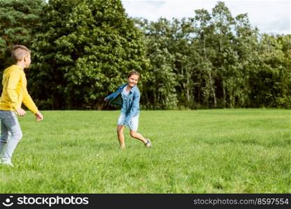 childhood, leisure and people concept - happy kids playing tag game and running at park. happy children playing and running at park