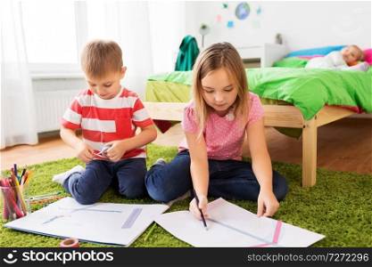 childhood, leisure and people concept - happy kids with paper, crayons and washi tape drawing and making crafts at home. children drawing and making crafts at home