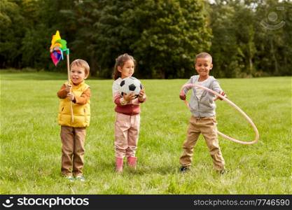 childhood, leisure and people concept - happy kids with pinwheel having fun at park. happy kids with pinwheel having fun at park