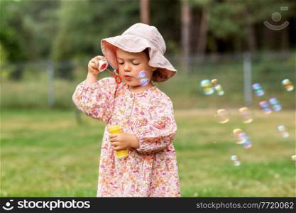 childhood, leisure and people concept - happy little baby girl blowing soap bubbles in summer. happy baby girl blowing soap bubbles in summer