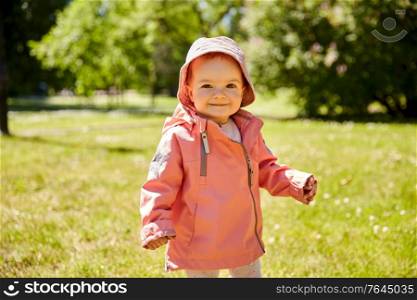 childhood, leisure and people concept - happy little baby girl in pink clothes at park in summer. happy little baby girl at park in summer