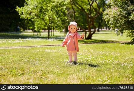 childhood, leisure and people concept - happy little baby girl in pink clothes at park in summer. happy little baby girl at park in summer