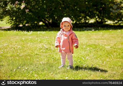 childhood, leisure and people concept - happy little baby girl in pink clothes at park in summer. happy little baby girl at park in summer