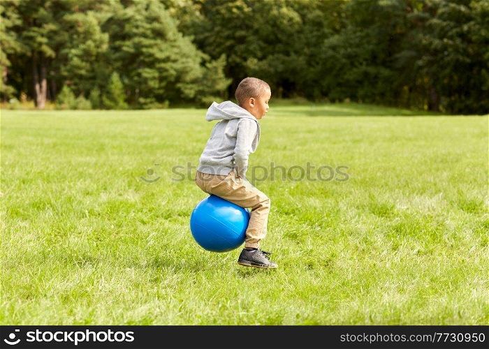 childhood, leisure and people concept - happy little boy bouncing on hopper balls at park. happy little boy bouncing on hopper balls at park