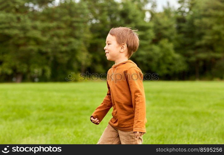 childhood, leisure and people concept - happy little boy running at park. happy little boy running at park