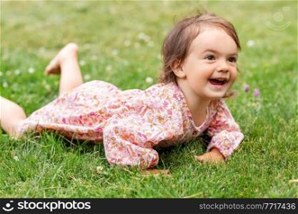 childhood, leisure and people concept - happy smiling little baby girl lying on grass in summer. happy little baby girl lying on grass in summer