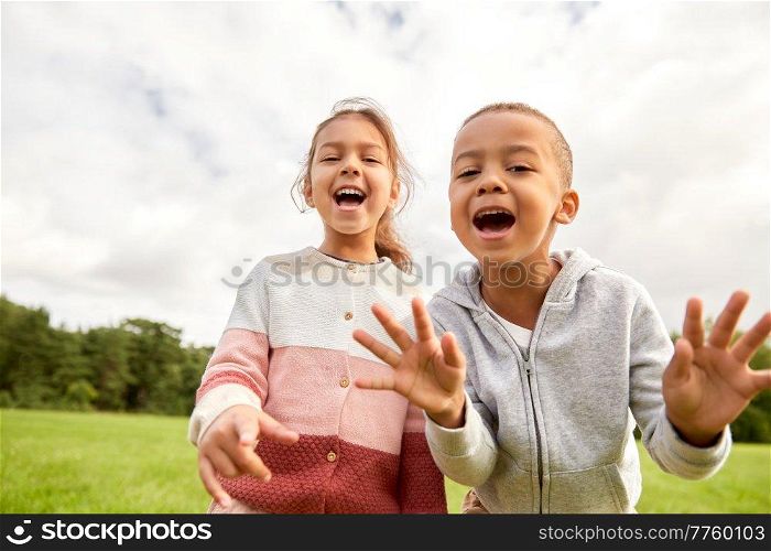childhood, leisure and people concept - happy smiling little boy and girl at park. happy little boy and girl at park