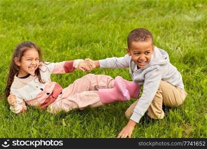 childhood, leisure and people concept - happy smiling little boy and girl having fun at park. happy little boy and girl having fun at park