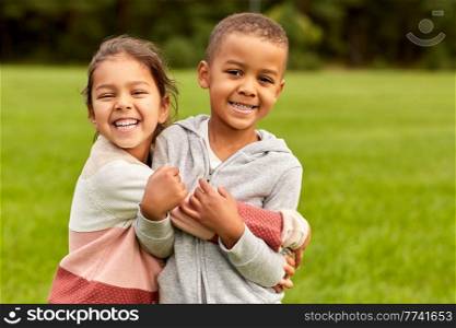 childhood, leisure and people concept - happy smiling little boy and girl hugging at park. happy little boy and girl hugging at park