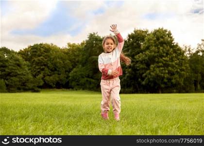 childhood, leisure and people concept - happy smiling little girl having fun at park. happy little girl having fun at park