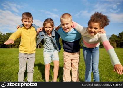 childhood, leisure and people concept - multiethnic group of happy children hugging at park. group of happy children hugging at park