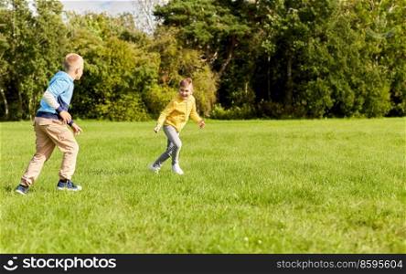 childhood, leisure and people concept - two happy boys playing tag game and running on lawn at park. two happy boys playing tag game at park