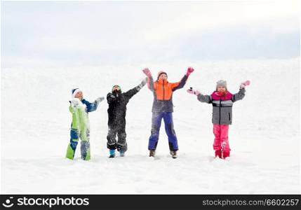 childhood, leisure and season concept - group of happy little kids in winter clothes playing with snow outdoors. happy little kids playing outdoors in winter