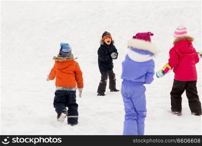 childhood, leisure and season concept - group of happy little kids in winter clothes playing outdoors. happy little kids playing outdoors in winter