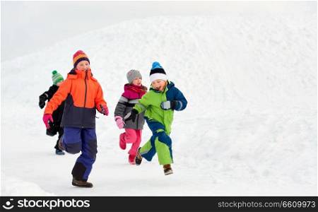 childhood, leisure and season concept - group of happy little kids in winter clothes running outdoors. happy little kids running outdoors in winter