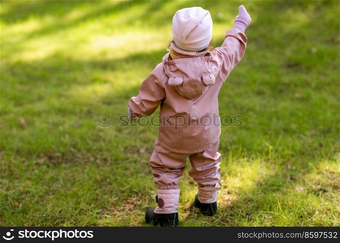 childhood, leisure and season concept - happy little baby girl pointing to something at autumn park. baby girl pointing to something at autumn park