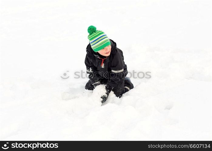 childhood, leisure and season concept - happy little boy playing with snow in winter. happy little boy playing with snow in winter