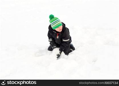 childhood, leisure and season concept - happy little boy playing with snow in winter. happy little boy playing with snow in winter