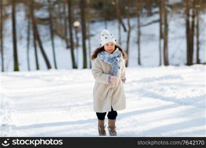 childhood, leisure and season concept - happy little girl in winter clothes running at park. happy little girl running at winter park