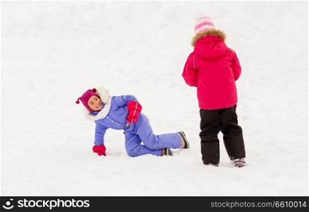 childhood, leisure and season concept - happy little girls in winter clothes playing outdoors in snow. happy little girls playing outdoors in winter