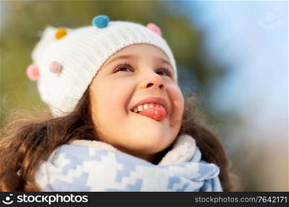 childhood, leisure and season concept - portrait of happy little girl having fun at winter park. happy little girl having fun at winter park