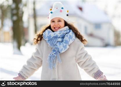childhood, leisure and season concept - portrait of happy little girl in winter clothes outdoors at park. happy little girl in winter clothes outdoors