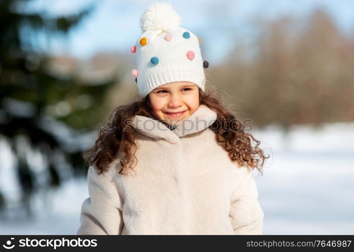 childhood, leisure and season concept - portrait of happy little girl in winter clothes outdoors at park. happy little girl in winter clothes outdoors