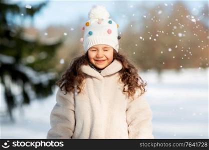childhood, leisure and season concept - portrait of happy little girl in winter clothes outdoors. happy little girl in winter clothes outdoors