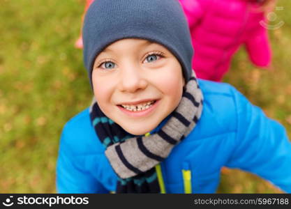 childhood, leisure, autumn and people concept - happy little boy face outdoors