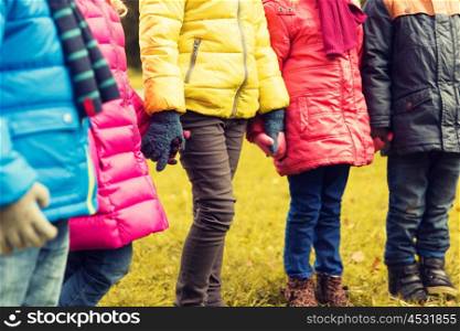 childhood, leisure, friendship and people concept - close up of happy children holding hands in autumn park
