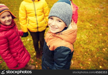 childhood, leisure, friendship and people concept - group of happy children holding hands and playing in autumn park