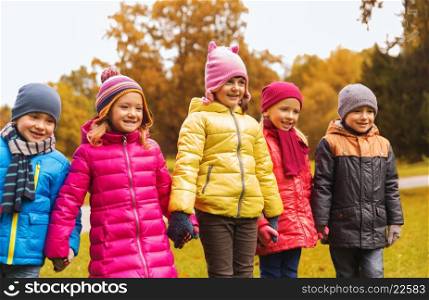 childhood, leisure, friendship and people concept - group of happy children holding hands in autumn park
