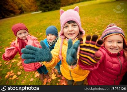 childhood, leisure, friendship and people concept - group of happy children waving hands in autumn park