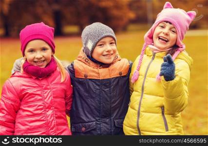 childhood, leisure, friendship and people concept - group of happy kids hugging and pointing finger on you in autumn park