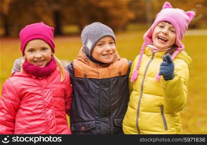 childhood, leisure, friendship and people concept - group of happy kids hugging and pointing finger on you in autumn park