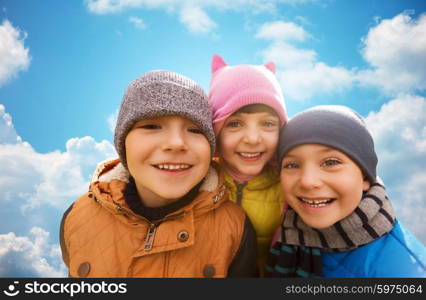 childhood, leisure, friendship and people concept - group of happy kids hugging outdoors over blue sky background