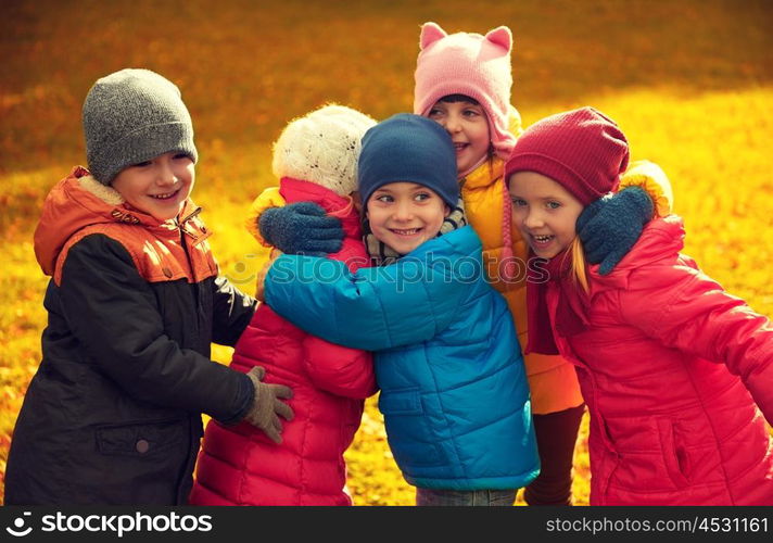 childhood, leisure, friendship and people concept - group of happy kids hugging in autumn park