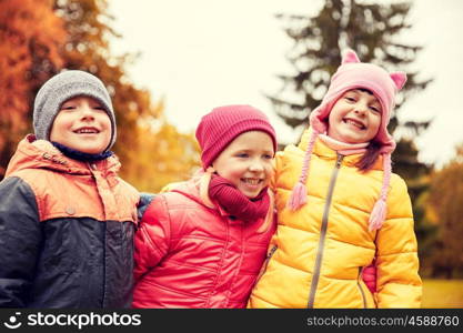 childhood, leisure, friendship and people concept - group of happy kids hugging in autumn park