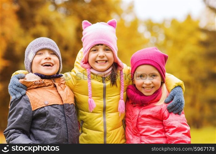 childhood, leisure, friendship and people concept - group of happy kids hugging in autumn park