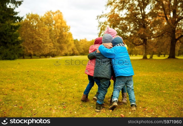 childhood, leisure, friendship and people concept - group of happy kids hugging in autumn park