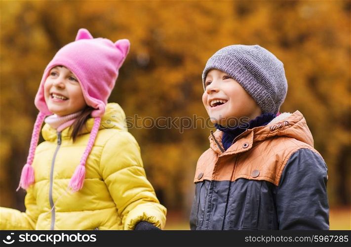 childhood, leisure, friendship and people concept - group of happy kids in autumn park