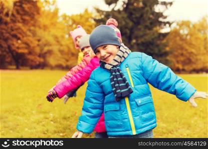 childhood, leisure, friendship and people concept - group of happy kids playing game and having fun in autumn park