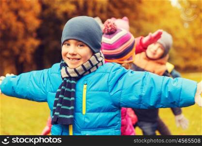 childhood, leisure, friendship and people concept - group of happy kids playing game and having fun in autumn park